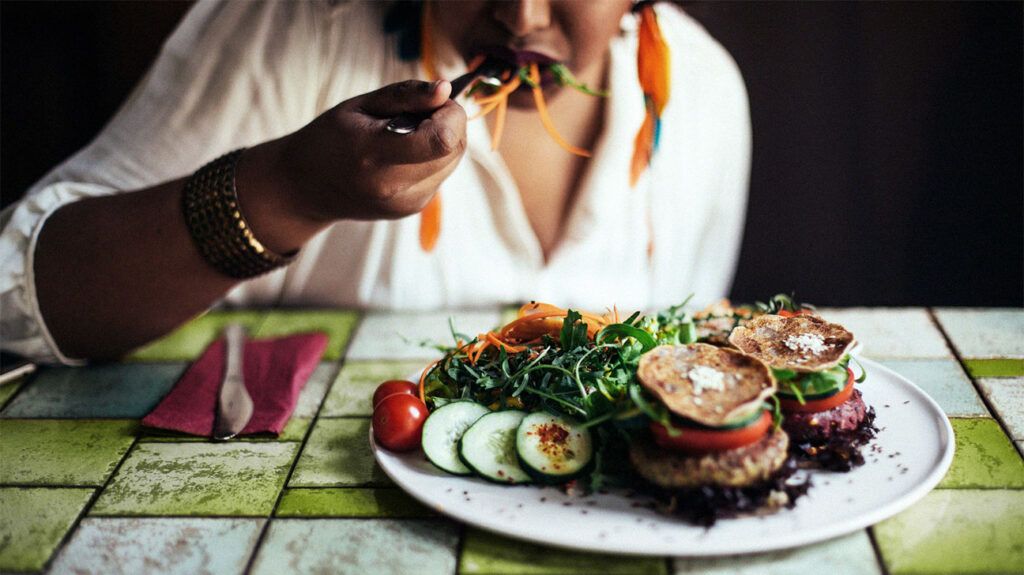 close-up on Black woman eating from a plate of vegetables