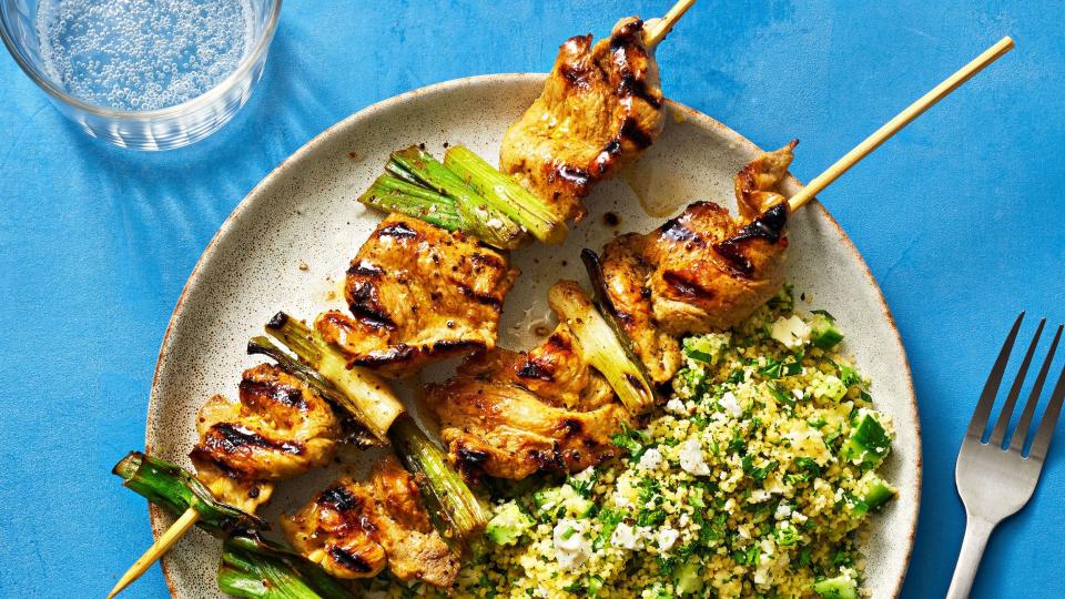 pork skewers on a plate with herby couscous