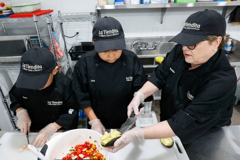 Intern Pedro Cuevas (left), 12, works on cutting shrimp as Junior Morelos (center), 16,...