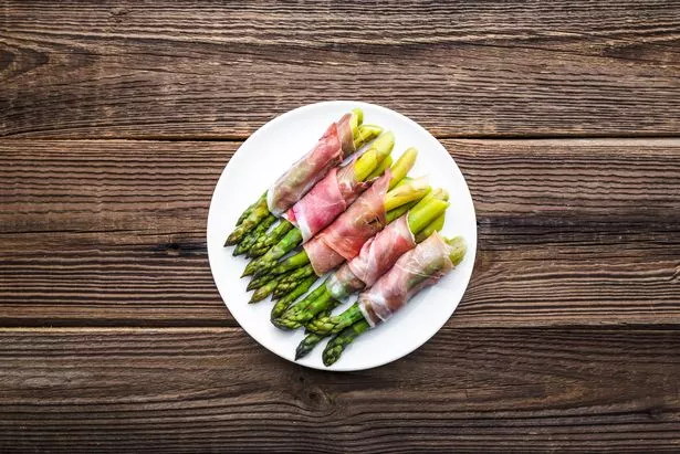 Cooked asparagus with ham. Appetizer with vegetable and meat, paleo food concept