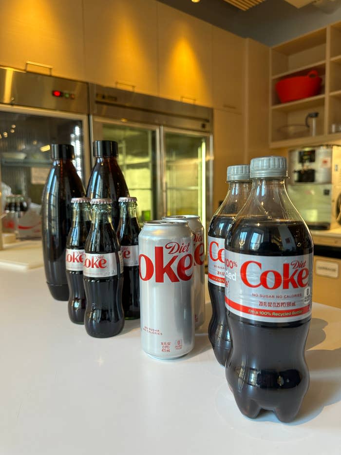 bottles and cans of diet coke lined up on a counter