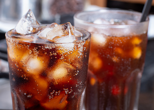 cola with crushed ice in glass and there is water droplets around. cool black fresh drink.