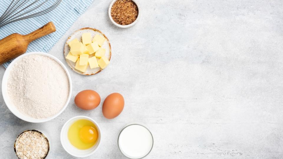 Baking ingredients eggs flour butter sugar and cooking utensils on grey concrete background. Top view copy space