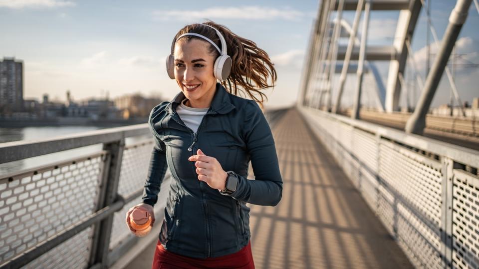 Young woman exercising outside, full of energy running across the bridge, healthy lifestyle