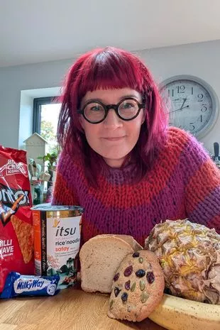 A picture of mum Claire Spreadbury wearing a pink and orange striped jumper in front of a range of foods that she and her family enjoy including bread, biscuits and tortilla chips