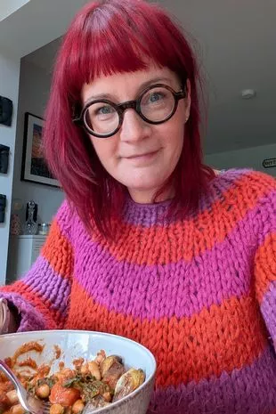 A picture of Claire Spreadbury, wearing a pink and orange jumper, eating a nutritious bowl of vegetables that she made herself