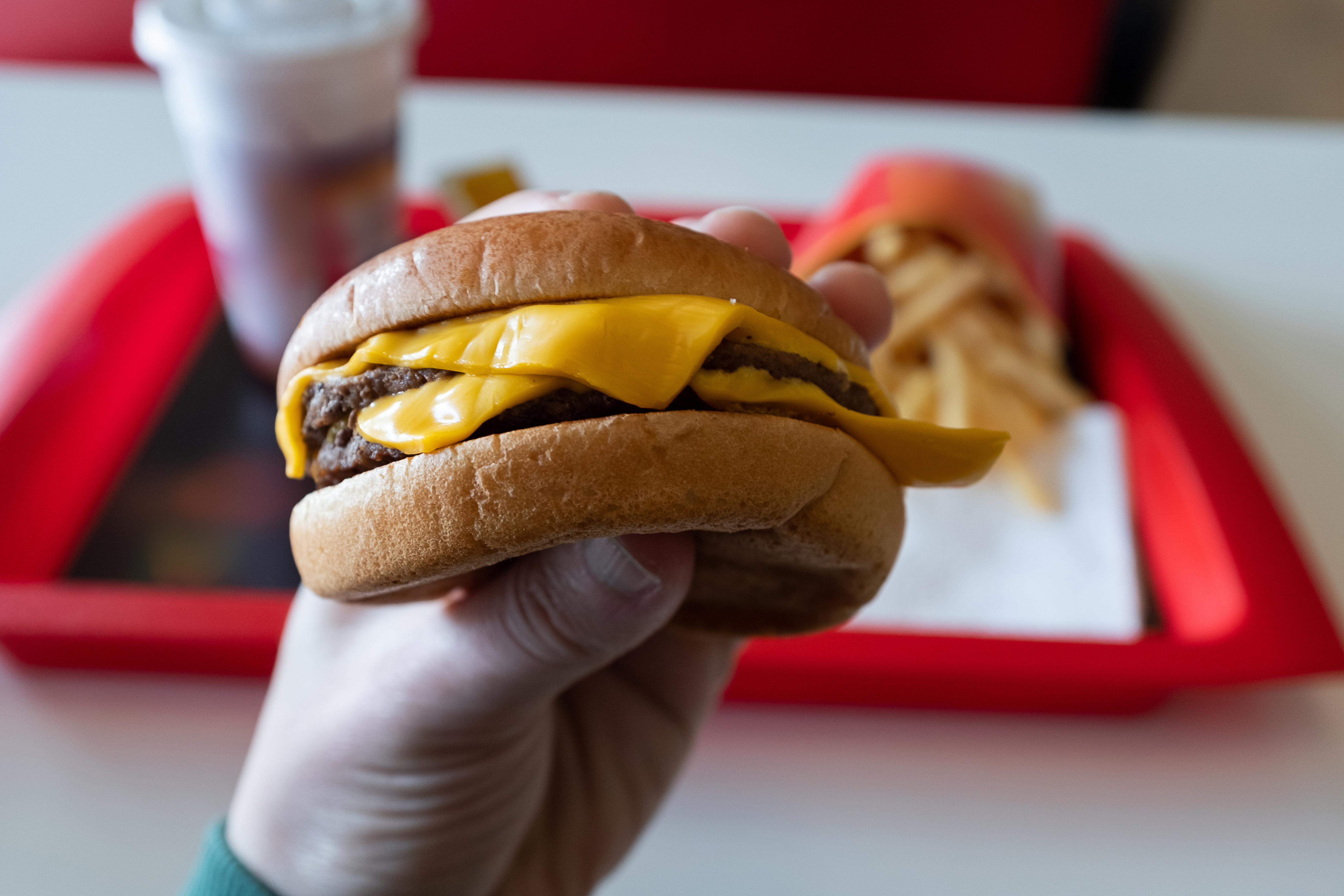 A person holding a cheeseburger.